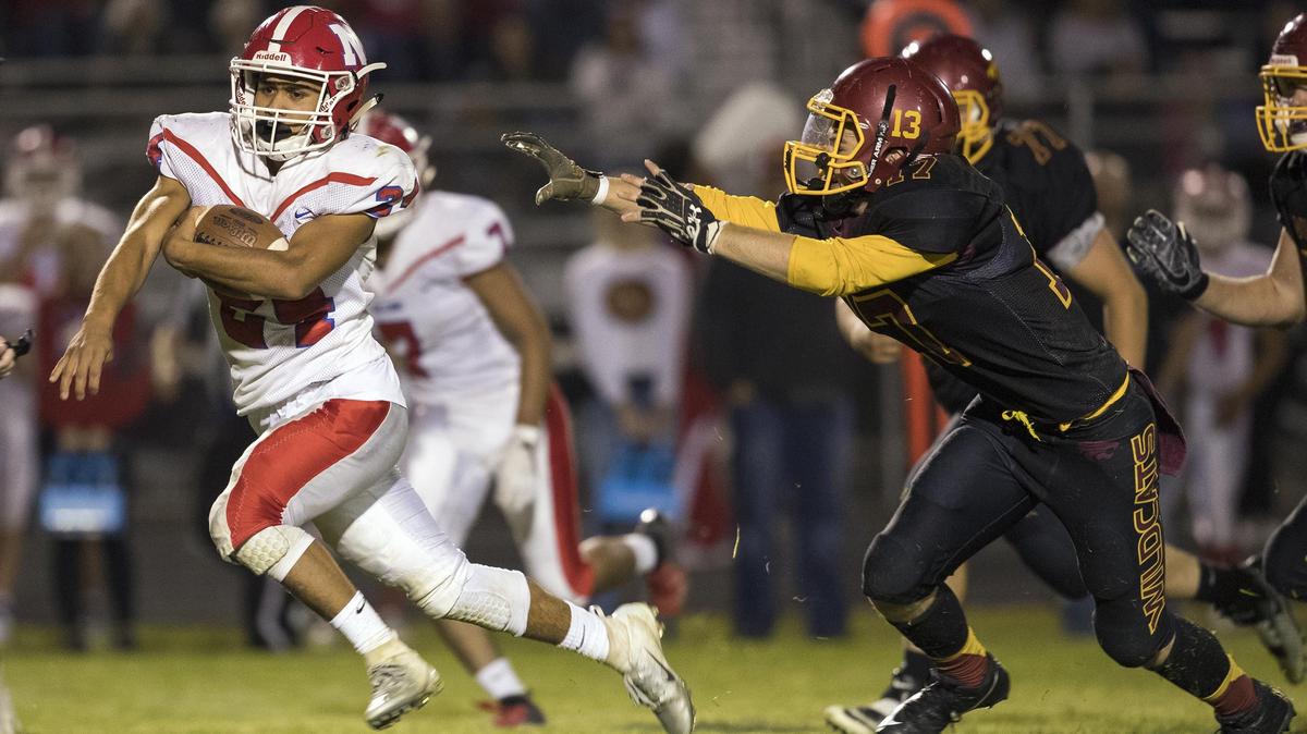 Nampa running back Brian Carrillo punches through into the Columbia secondary, evading Columbia linebacker Jake Rowan on Friday, Sept. 28, 2018, at Columbia High in Nampa. The Bulldogs won 49-21.