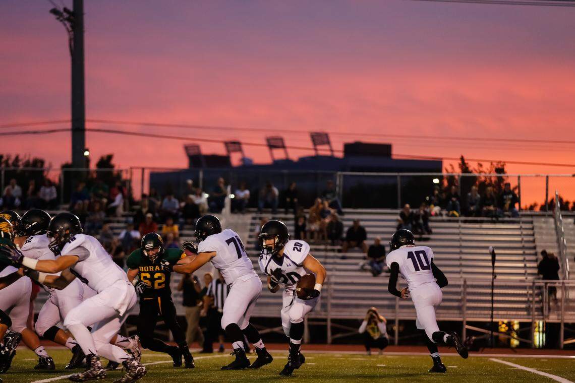The sun sets behind Dona Larsen Park and the lights of nearby Albertsons Stadium loom in the background of a 2015 game between Borah and Rocky Mountain.