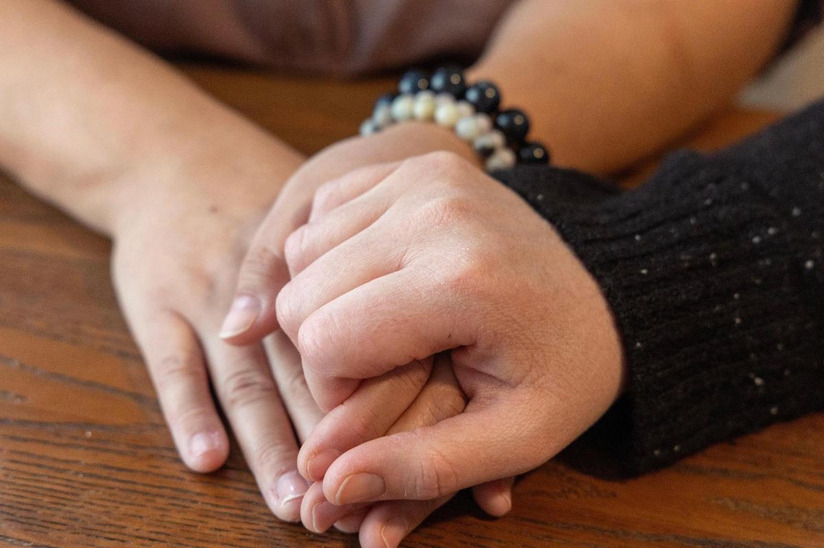 Chelsea Gaona-Lincoln, left, and Van Beechler-Lincoln hold hands at their home in Boise.