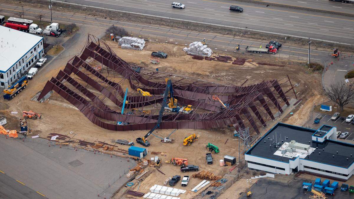 This aerial photo looking north shows the hangar wreckage in center with cars traveling on Interstate 84 at top. A Firehawk Helicopters building can be seen at left and Jackson Jet Center at right.