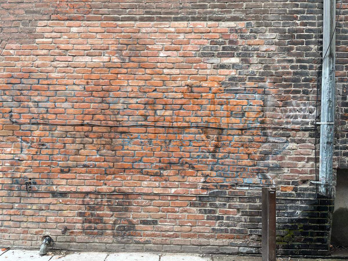 A washed-down section of Freak Alley Gallery opposite Bespoke Custom Clothing that had been vandalized. Graffiti tags still remain visible on the wall.