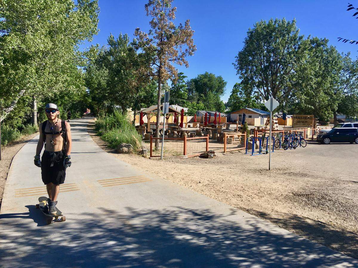 A skateboarder in Garden City rides along the Greenbelt. Behind him, Hannah Ball’s 34th Street market is closed on a Thursday night.