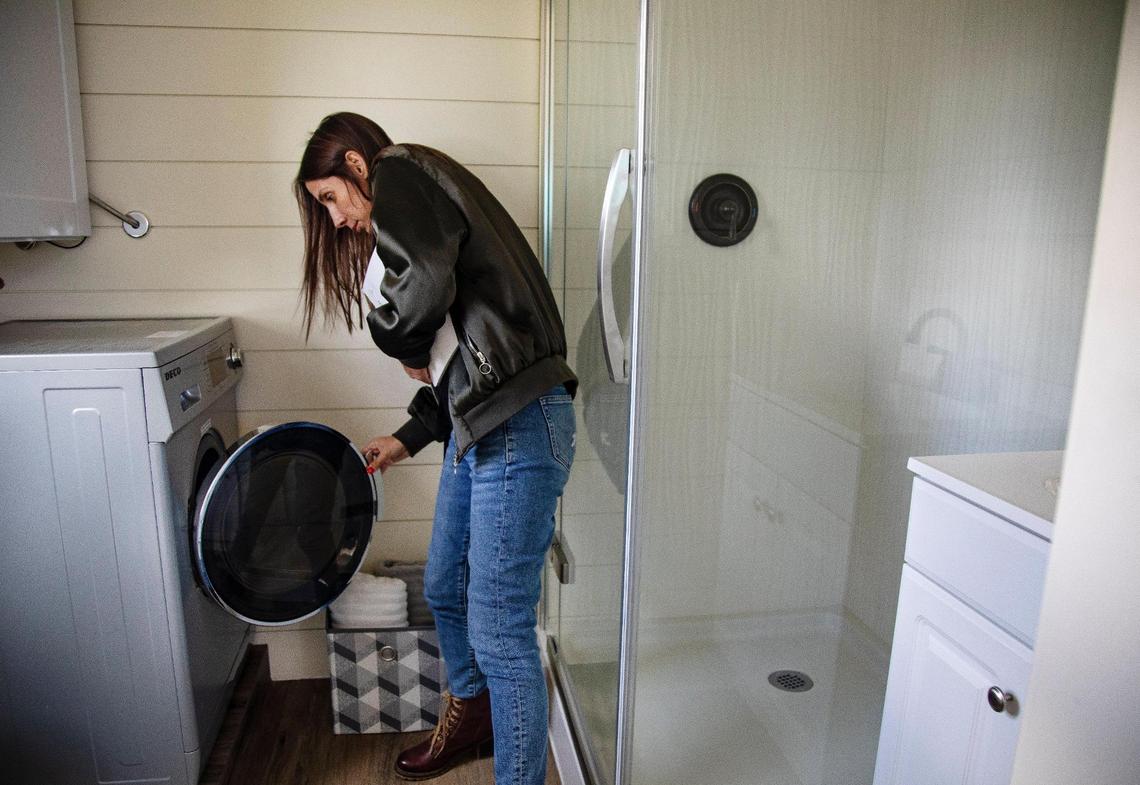 Developer Hannah Ball opens the washing machine in the bathroom of a tiny home she has on display in Garden City. Ball believes that tiny homes are an affordable housing option that should be available in Garden City; however, they are currently illegal to reside in.