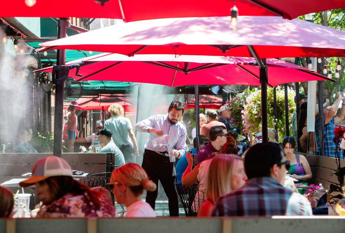 Waiter David Kan serves cold water to restaurant patrons on the patio of Bardenay in the Basque Block of downtown Boise on July 30, 2022. Temperatures above 100 degrees are expected over the weekend.