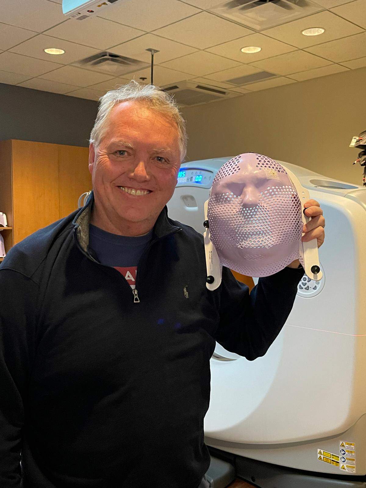 Fred Cornforth holds up a mask that’s used to hold him still while he receives radiation treatments for glioblastoma, a terminal brain cancer that he was diagnosed with in December.