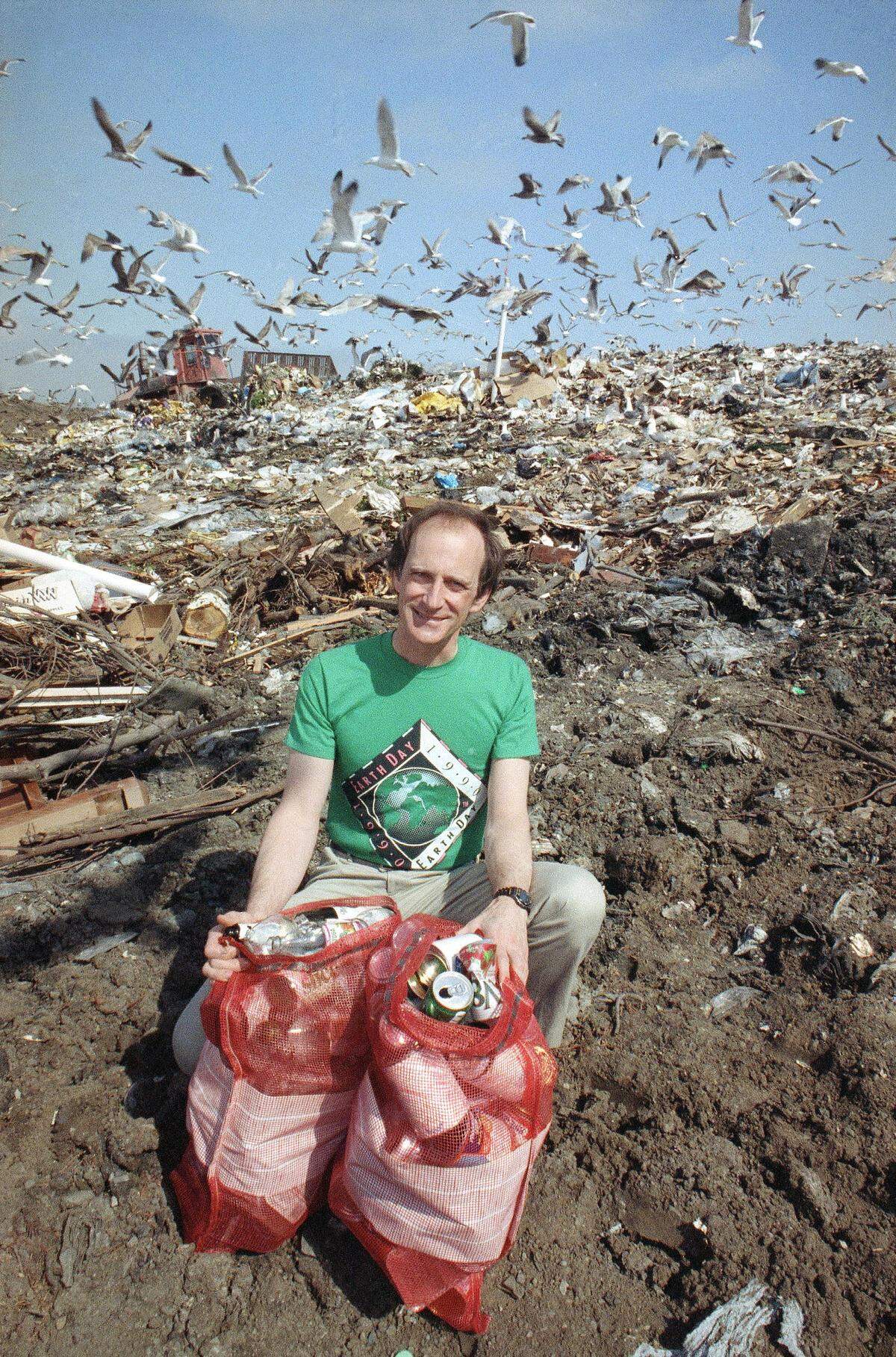 Earth Day founder and Palo Alto, California resident Denis Hayes at a dump site in Palo Alto, California on April 5, 1990, as he displays burlap sacks filled with empty glass bottles and metal cans that local residents use in a weekly recycling program. Hayes urges all people to recycle as an alternative to dumping. (AP Photo/Paul Sakuma)