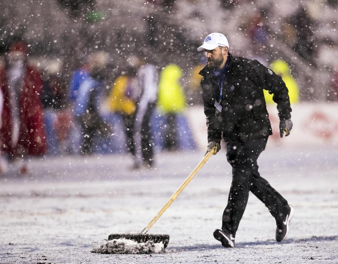 Heavy snow kept crews busy clearing markers on the blue turf of Albertsons Stadium during the Boise State vs. Fresno State Mountain West championship game.