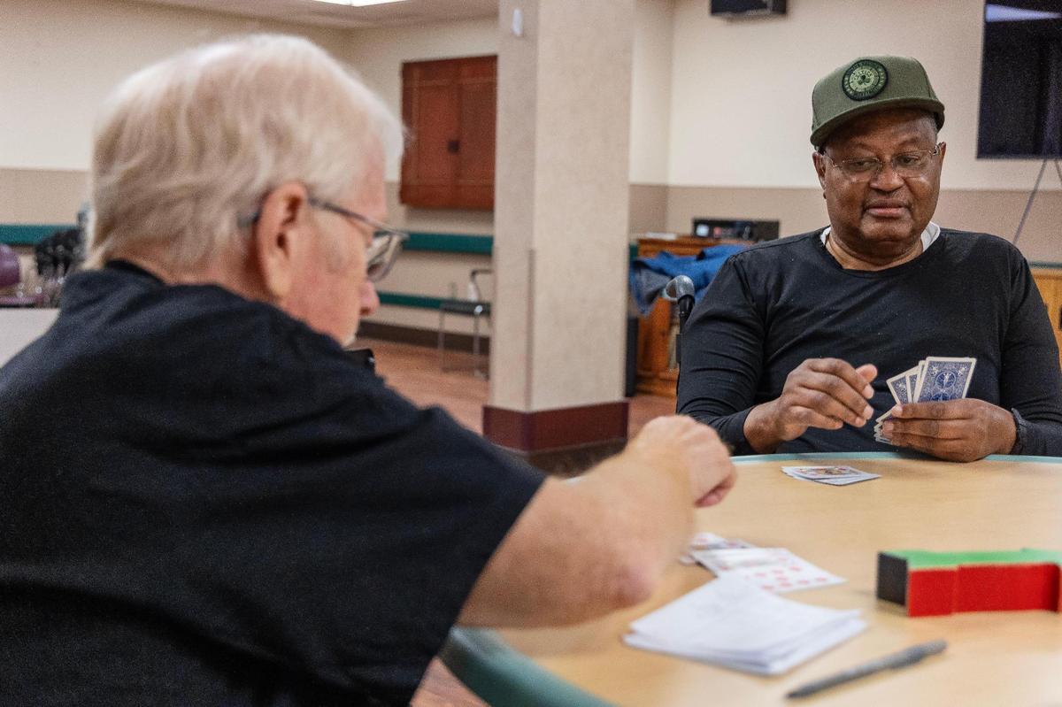 Volunteer Ed Samuel, left, plays pinochle with resident Aaron Thomas, right, in one of the activity centers.