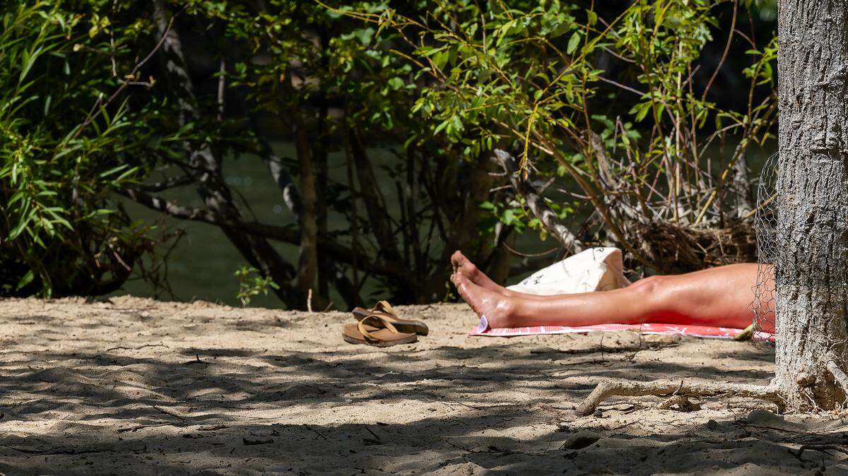 A woman sun-bathes along the Boise River in July 2023, when temperatures were in the mid-90s.