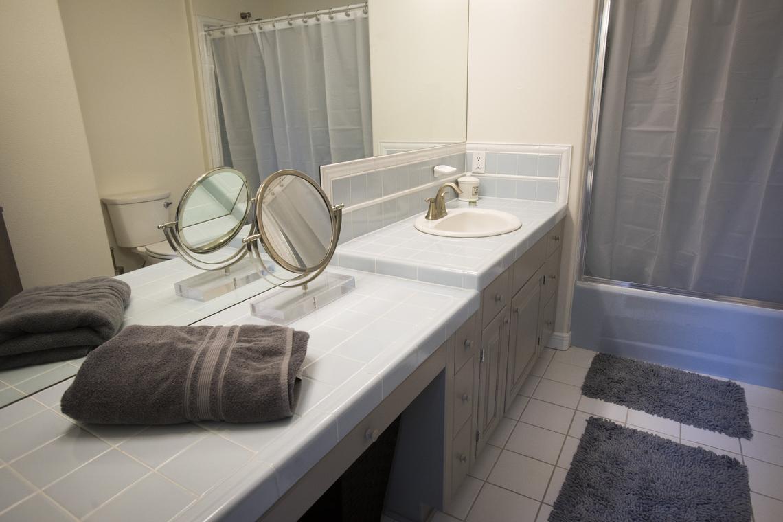 Bill and Calie Wendlandt decided to wait to remodel the other  three bathrooms. They cleaned up original tile, like the 1980’s pale blue, and repainted the cabinets a more contemporary gray.