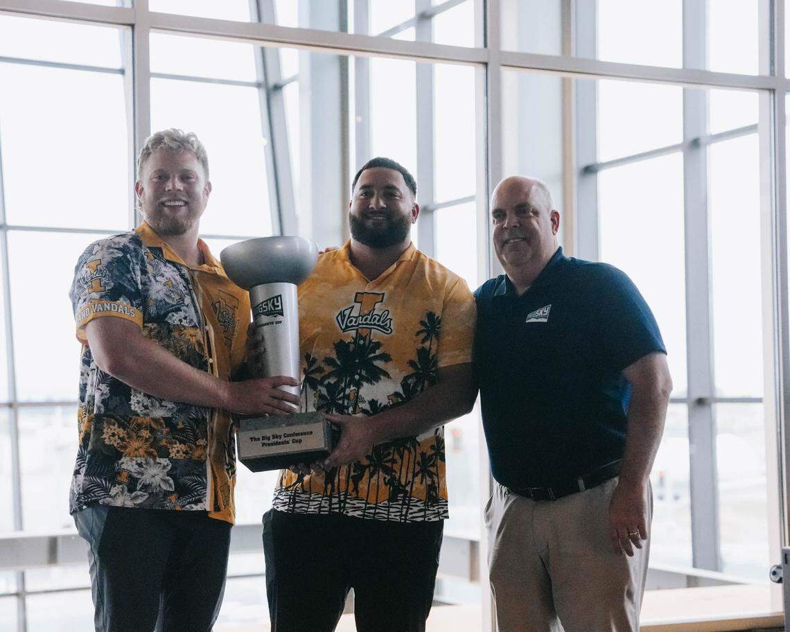 Idaho defensive lineman Sam Brown, from left, offensive lineman Nate Azzopardi and Big Sky Conference Commissioner Tom Wistrcill show off the traveling Big Sky Conference Presidents’ Cup, which was awarded to the Vandals for the 2024-25 school year.