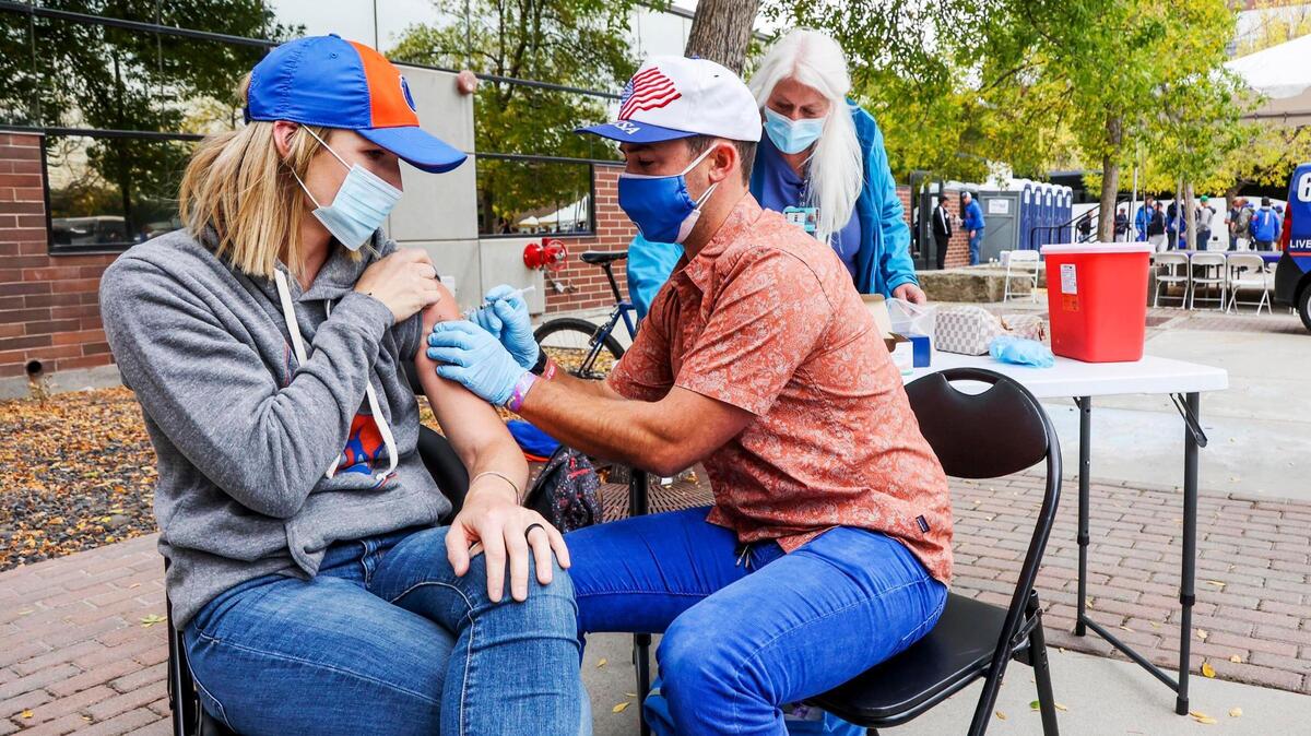 Shalyn Blaisdell, of Kuna, receives a dose of COVID-19 vaccine from Boise State nursing program student Dane Larson outside Albertsons Stadium on Sept. 18. She was attending the Broncos’ football game with Oklahoma State.
