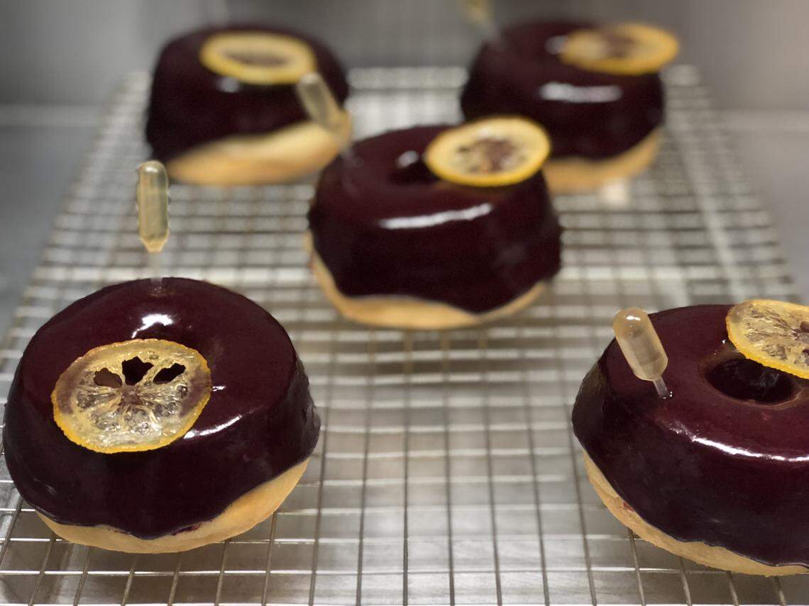 The 99 Problems But ... : A brioche donut topped with blueberry-basil glaze and candied lemon, impaled with a pipet of honey bourbon.