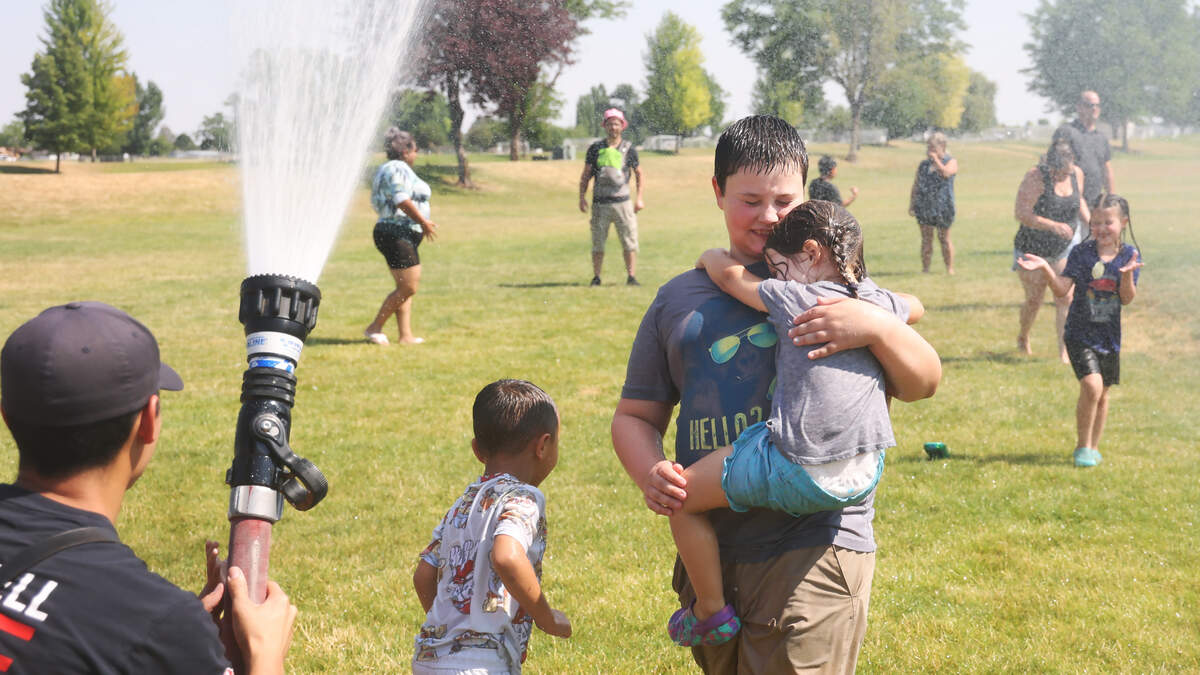 Caldwell firefighter Mike Aguilar sprays water into the air for children and families to enjoy at Brothers Park in Caldwell in July.