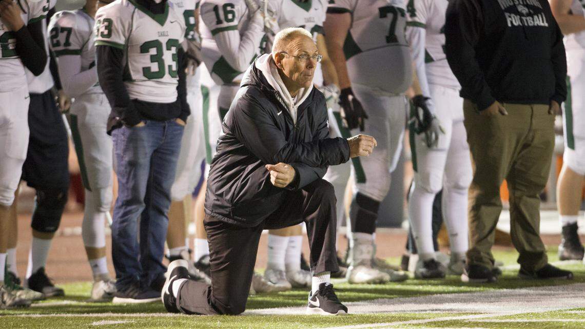 Eagle football coach Paul Peterson takes a knee on the sideline during a 36-32 win over Capital at Dona Larsen Park last fall.