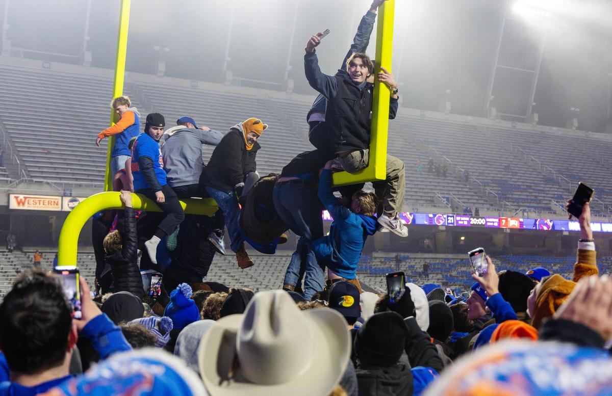 People storm the field and try to knock over the goalpost after Boise State’s win in the Mountain West championship game against UNLV.