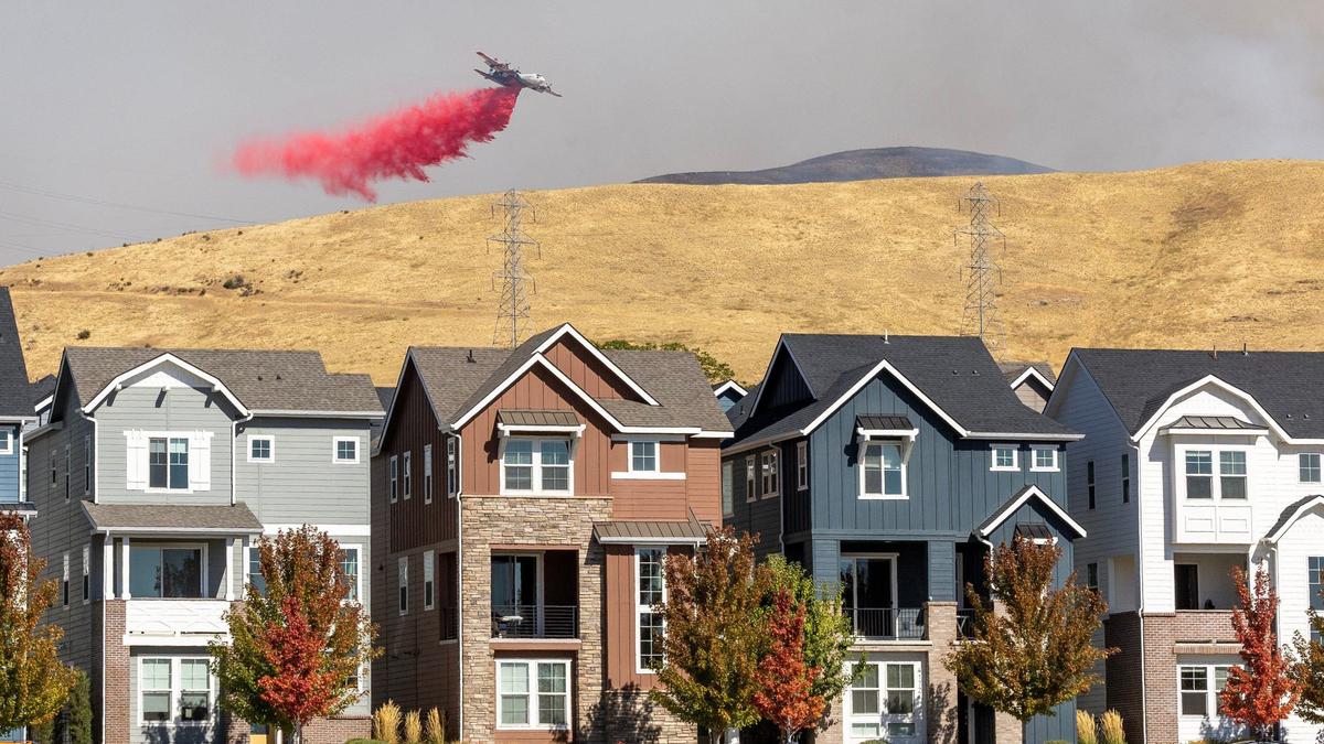 A plane drops fire retardant just north of homes in Harris Ranch on Friday.