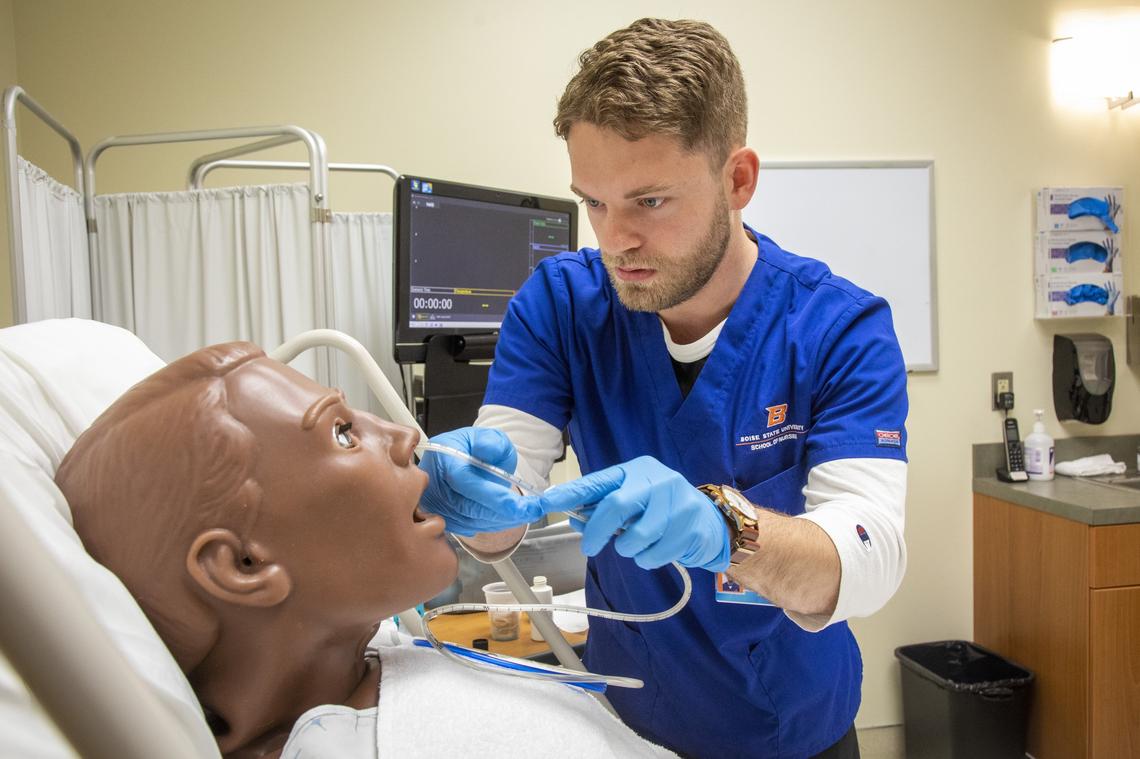 Graham Dowdy, a third-year nursing student at Boise State, places a nasogastric feeding tube into a mannequin. The mannequin can be programed to have human symptoms, reactions and interactions to make the scenario as realistic as possible for students.