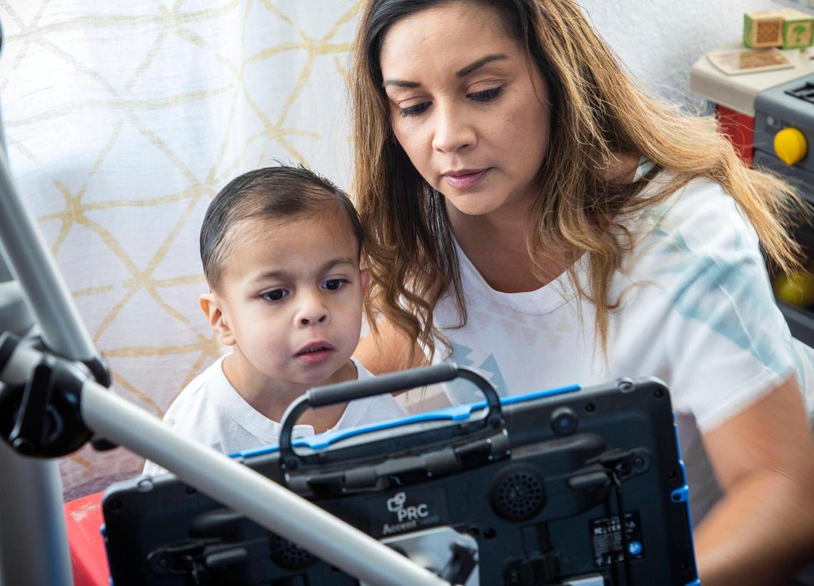 Jessica Mandujano helps her son Joaquin, 5, learn to use a device that tracks his eye movement to interact with applications on the screen. He is diagnosed with Emanuel syndrome, a rare chromosomal disorder that limits childhood development on multiple levels. She hopes the device will help Joaquin learn to communicate since most people with Emanuel syndrome are nonverbal. Teachers at his developmental school have yet to train with him on the device, which Jessica said they just acquired at the onset of the coronavirus pandemic.