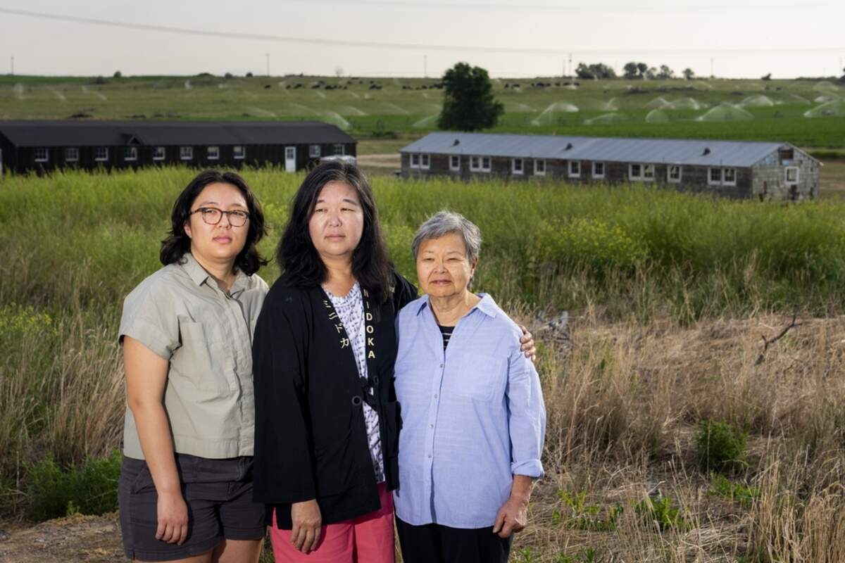 Minidoka survivor Mary Tanaka Abo, 83, at right, poses for a portrait with daughter Julie Abo, center, and granddaughter Maya Abo Dominguez, left, in front of a historic mess hall and barracks. Tanaka Abo says she didn’t want Julie or Maya to feel the same sense of shame surrounding incarceration as she did. Instead, she chose to speak openly about her experience with her daughter and granddaughter, and has attended multiple pilgrimages with her family.