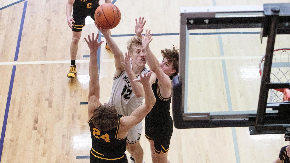 Middleton senior Tyler Medaris fights past Bishop Kelly’s Blake Hawthorne, left, and Mason Rossi to score two of his 10 points in the Vikings’ first-round victory Thursday at Rocky Mountain High School.