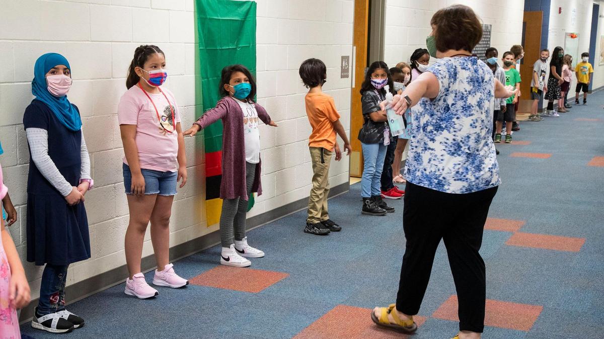 Wearing protective masks and keeping social distancing in mind, teacher Donde Llamas helps students form a line at Morley Nelson Elementary in Boise. Boise School District officials plan to propose an updated health and safety plan later this month that makes masks optional for students and staff, and is asking parents, students and staff members for feedback.
