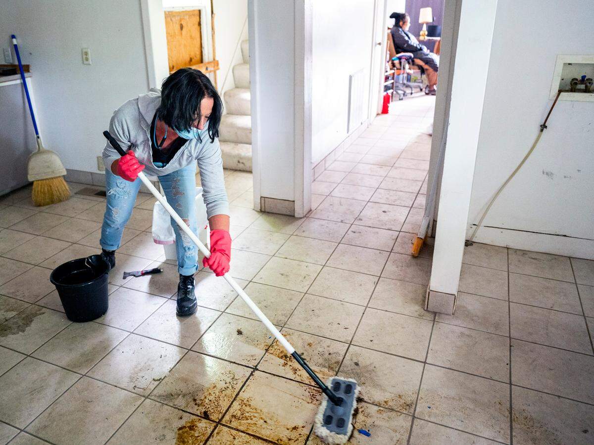 On Thursday afternoon, Amber Haning scrubs the kitchen floor in the home of Helen Wong as a group of kind-hearted volunteers work on deep cleaning the home that was left destitute by a group of squatters in Lewiston. The squatters took advantage of Wong’s long absence after she got stuck in Hong Kong while visiting family. She could not travel back to her home in Lewiston because of the COVID-19 global pandemic travel restrictions.