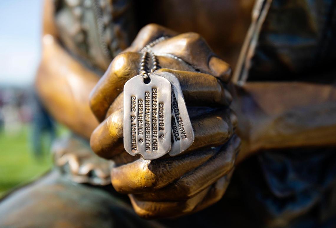 The male figure in the statue holds dog tags of fallen service members.