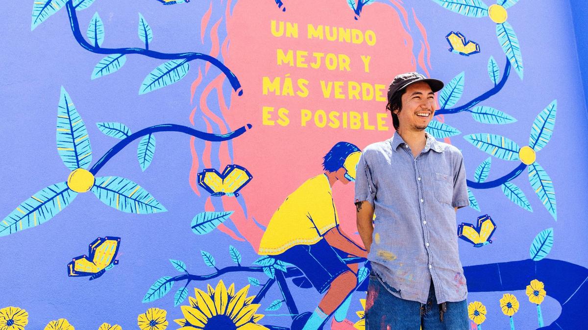 Miguel Almeida stands up against a mural he painted in Garden City that says in Spanish: “A better and greener world is possible.”
