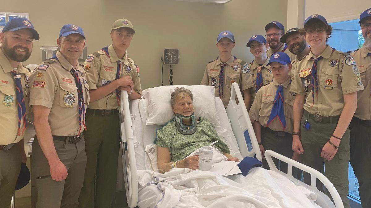 Eric Valentine poses with members of Troop 77 from his hospital bed Monday evening. Nearly two dozen members of the troop were on a canoe trip on May 6 when they were flagged down and able to help Valentine after he fell in Hells Canyon.