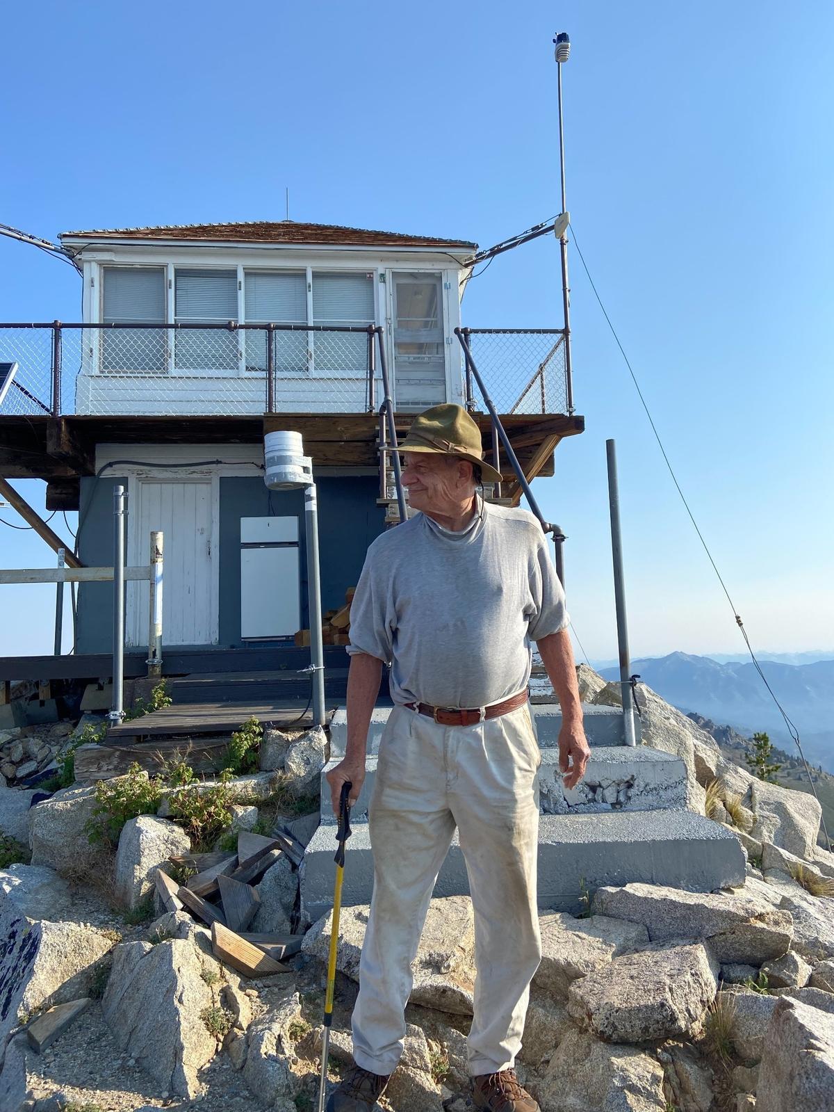 Jon Fredland poses in front of the fire lookout at the top of Trinity Mountain on Aug. 4. Fredland’s ascent of Trinity Mountain marked his 3,000th summit.