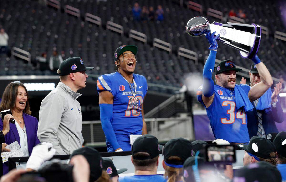 Boise State safety Alexander Teubner (34) celebrate with the Mountain West championship trophy after the Broncos’ 44-20 win over UNLV Saturday at Allegiant Stadium in Las Vegas.