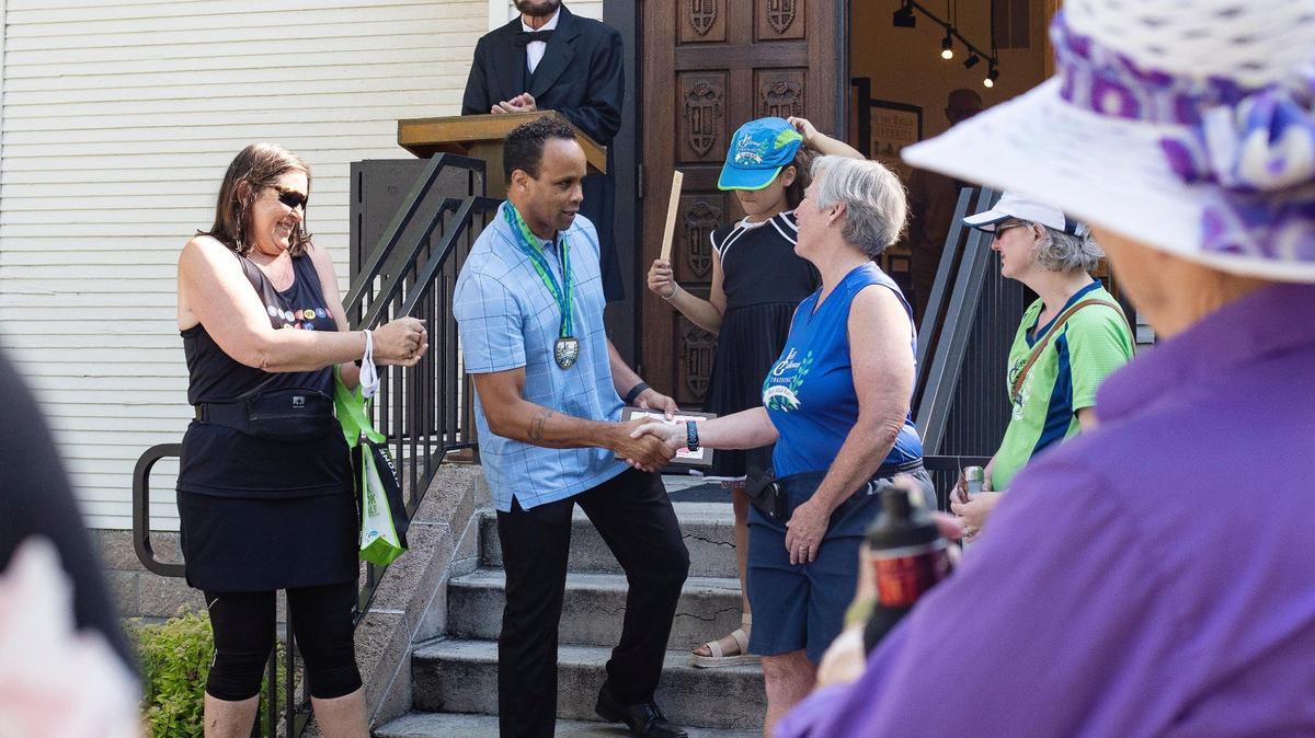 Phillip Thompson, board president of the Idaho Black History Museum, shakes hands with Jayne Black as she and members of Boise Galloway Training award $1,600 to the museum from a 10k Juneteenth run the group sponsored in 2021, the first year that Juneteenth was a federal holiday.