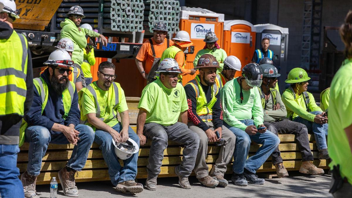 Tradespeople and construction workers attend the topping-out ceremony.