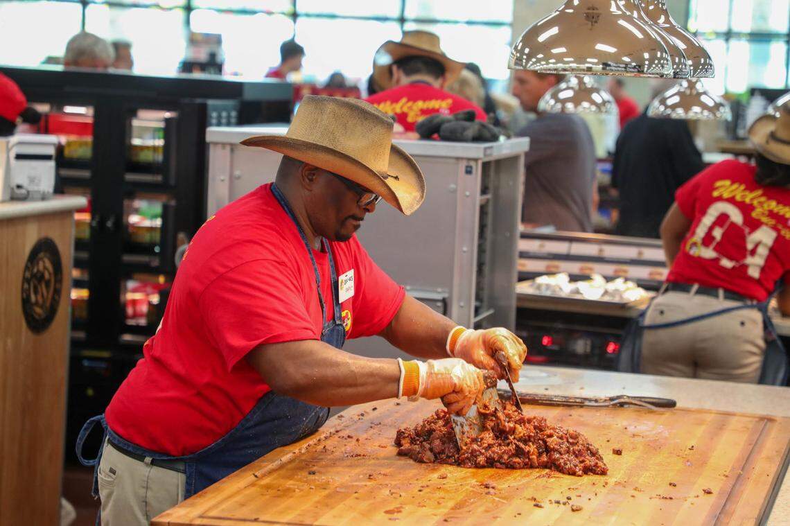 An employee chops up sauced BBQ during the grand opening of Buc-ee’s in Brunswick, Georgia.