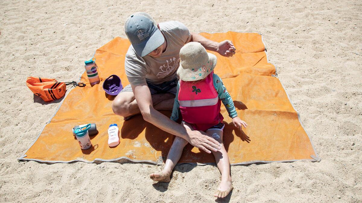 Dave Womak puts sunscreen on his daughter Grey, 2, while they visit Lucky Peak State Park on Wednesday.