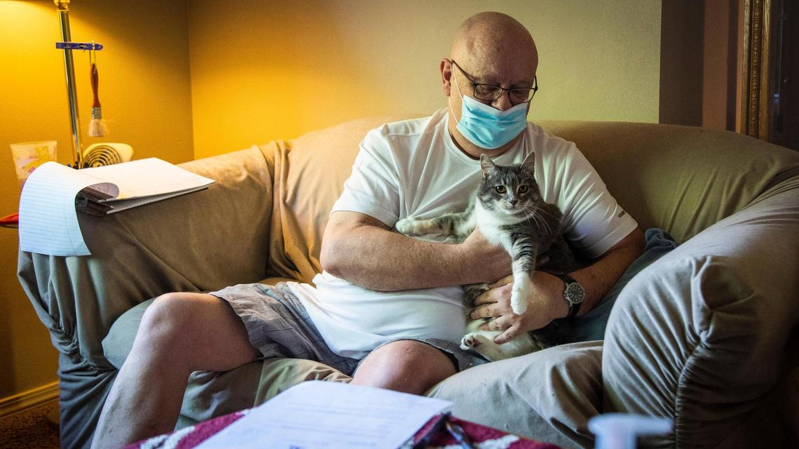 Chuck Bunch plays with one of his three cats while talking about his fears of leaving his apartment in Nampa after a property management company served him with a 30-day notice.