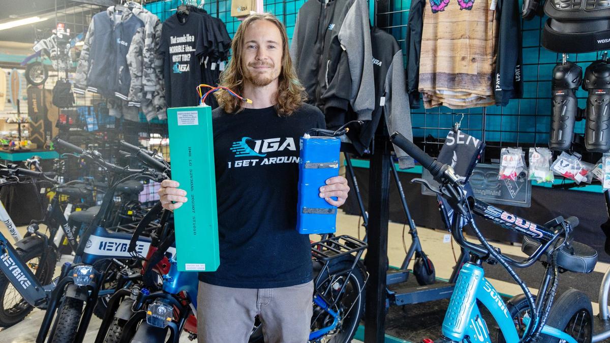 Ben Bernquist holds some of the batteries from electric bicycles and other devices that customers have dropped off at I Get Around. The Boise store sells battery-powered bikes, scooters, longboards and unicycles.