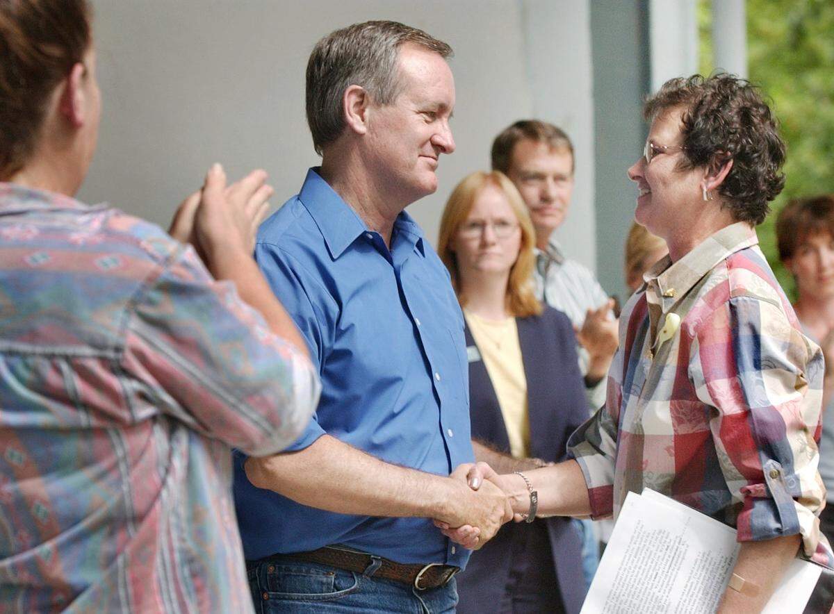 Sen. Mike Crapo (center) shakes hands with "downwinder" activist Sheri Garmon at a town meeting in Emmett in 2004. Garmon died of cancer the following year.
