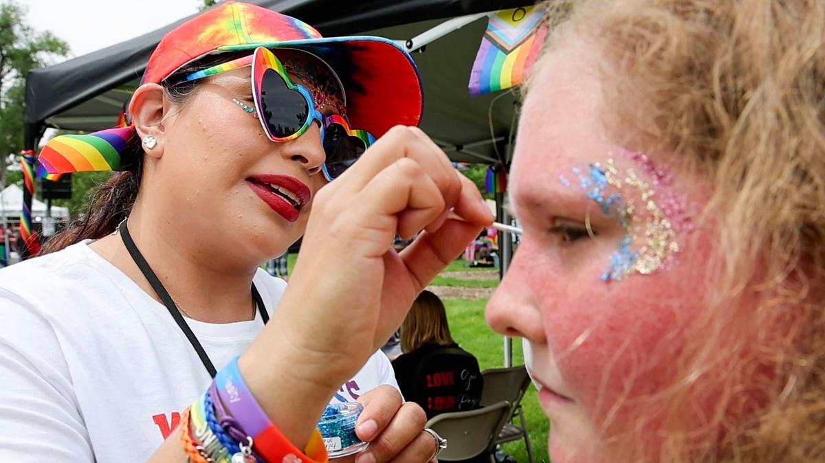 Christina Snyder paints glitter rainbows on the forehead of Hailey Colegrave at the first Canyon Canyon Pride Festival.