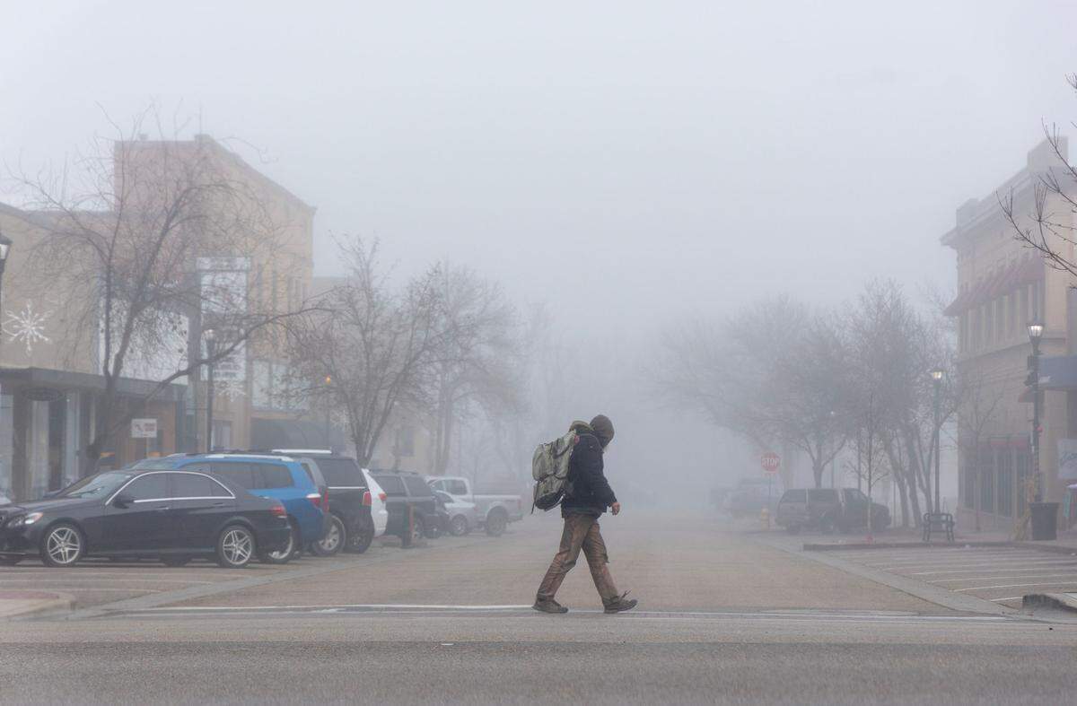 A man walks through downtown Nampa in heavy fog on Wednesday.