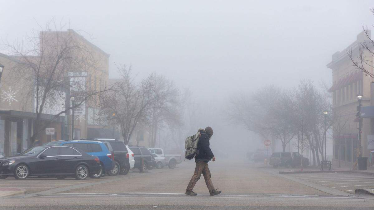 A man walks through downtown Nampa in heavy fog on Dec. 20, 2023.