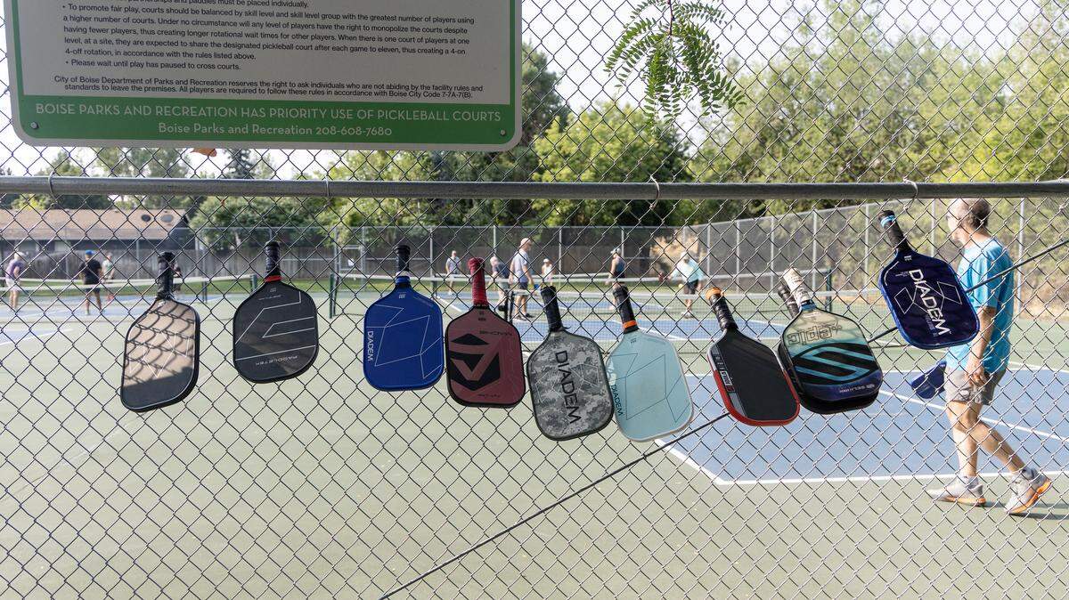 People line up their paddles along the fence Friday at the Manitou Park pickleball courts.