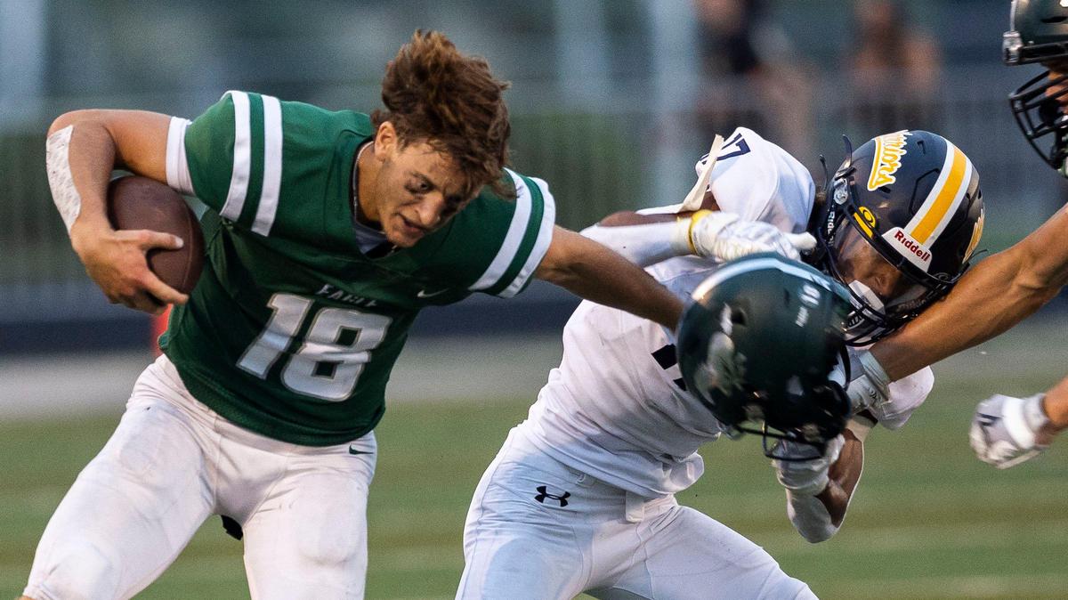 Eagle quarterback Davis Harsin loses his helmet but keeps racking up yards Friday night at Eagle High. Meridian’s Kalani Reynolds, back, was flagged for a face mask in the 5A SIC season opener for both teams.