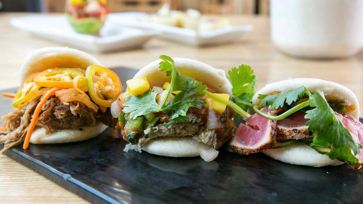 Steamed sesame seed bao buns provide the mouthwatering carrying case for Naked Fins’ crushable baos: From left, a Pork Bao ($1.75 for slow-braised pork, house-made kimchi, fresh jalapeño, bao sauce), Chicken Bao ($1.75 for green-chili-braised Red Bird chicken, pico de gallo, fresh cilantro, house-made salsa) and Seared Ahi Bao ($2 for ahi tuna tataki, cucumber salad, fresh cilantro, Thai peanut sauce).