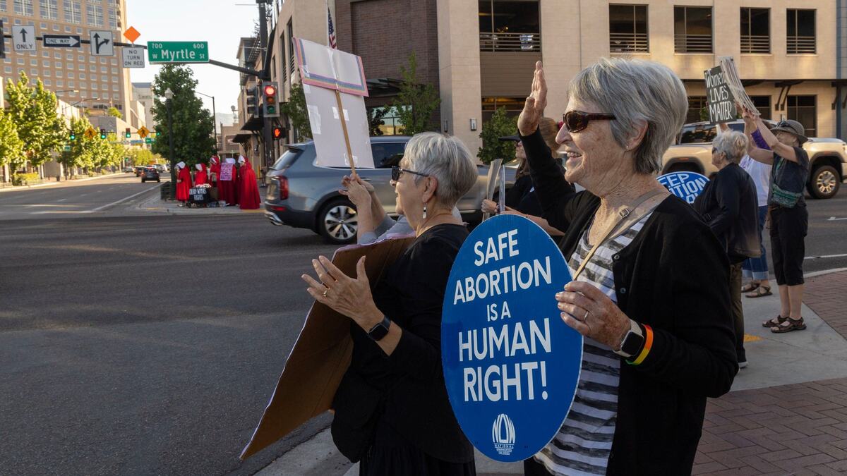 Kate Brock, right, and Audrey Numbers wave signs supporting women’s reproductive rights at oncoming commuter traffic on the corner of Myrtle Street and Capitol Boulevard in Boise on Monday.