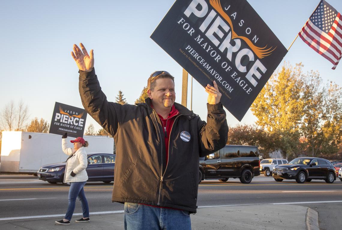 Jason Pierce, along with his wife, Jennifer, and other supporters, waves to early morning commuters at Highway 55 and Eagle Road. Pierce defeated incumbent Mayor Stan Ridgeway, capturing 52.7% of the vote.