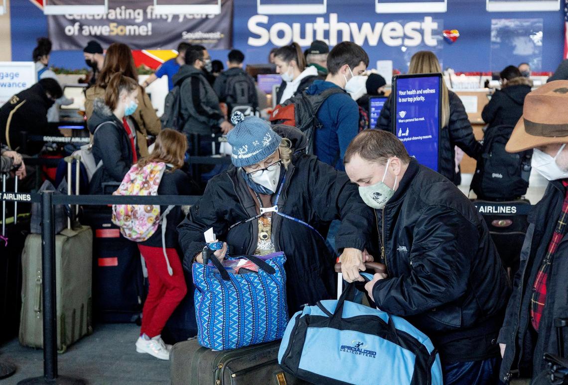 Julie Dewey, left, her son Devan Dewey, center, and husband David Dewey move forward in the Southwest Airlines luggage drop line as they travel back to San Jose, California, from the Boise Airport on Tuesday, Dec. 28, 2021.