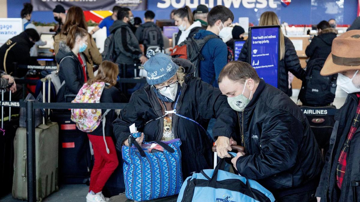 Julie Dewey, left, her son Devan Dewey, center, and husband David Dewey move forward in the Southwest Airlines luggage drop line as they travel back to San Jose, Calif. from the Boise Airport on Tuesday, Dec. 28, 2021.