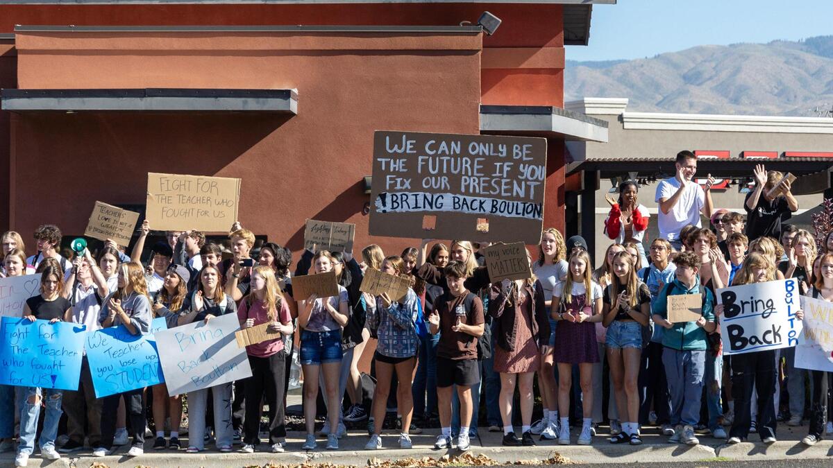 Timberline High School students stand on the sidewalk across the street from their school Thursday after staging a walkout to protest teacher Laura Boulton’s suspension.